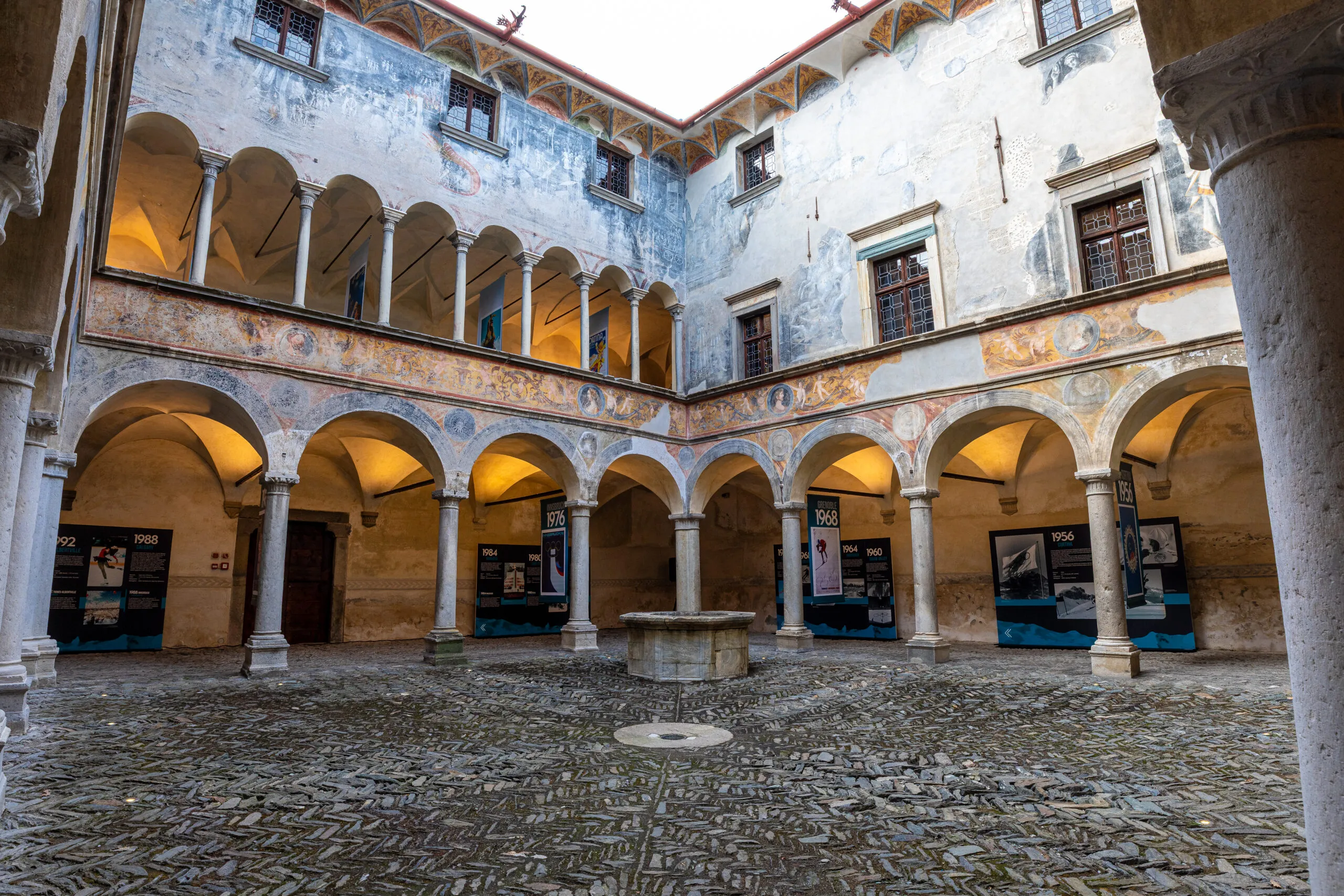 Nella corte di Palazzo Besta, dalle proporzioni perfettamente cubiche, manifesti storici e pannelli ripercorrono la storia delle Olimpiadi e Paralimpiadi invernali.